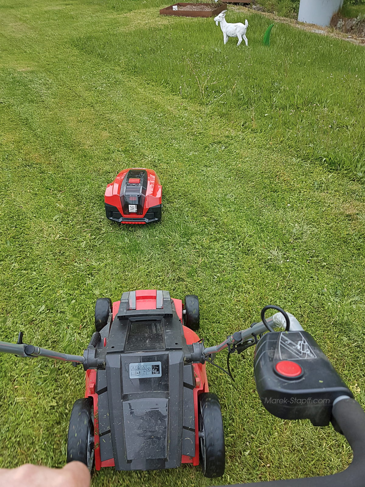 Elektrischer Rasenmäher fährt hinter einem modernen Mähroboter her