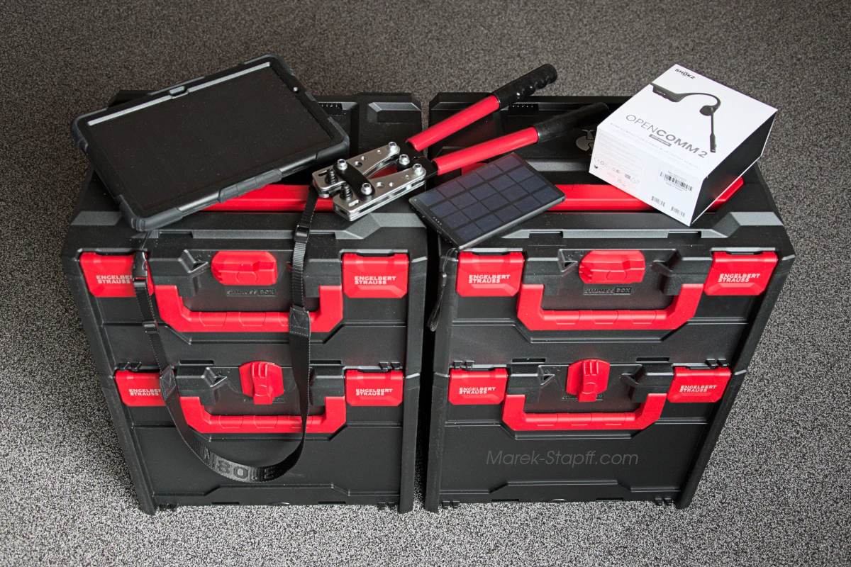 Werkzeug und Ausrüstung eines Automatisierers: Transportboxen, Presszange, Tablet mit Schutzhülle und Knochenschall-Kopfhörer